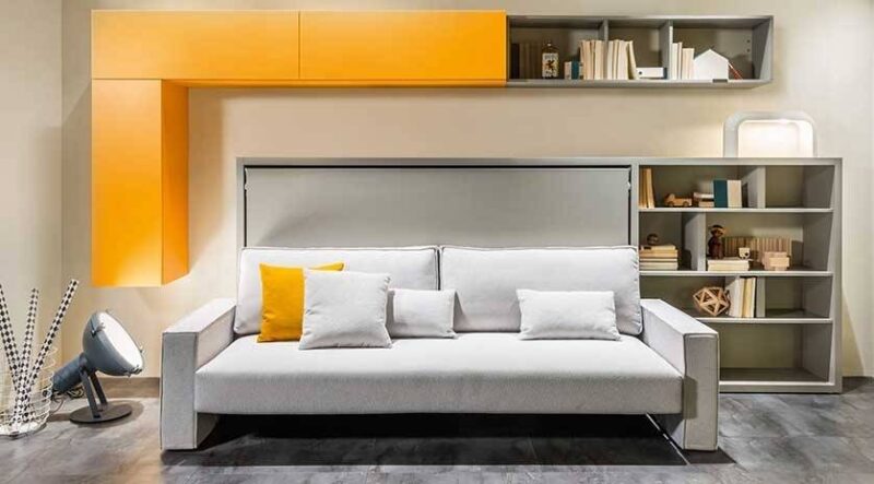 mueble con sofá cama abatible horizontal. Combinación de gris y amarillo con estantes a juego.