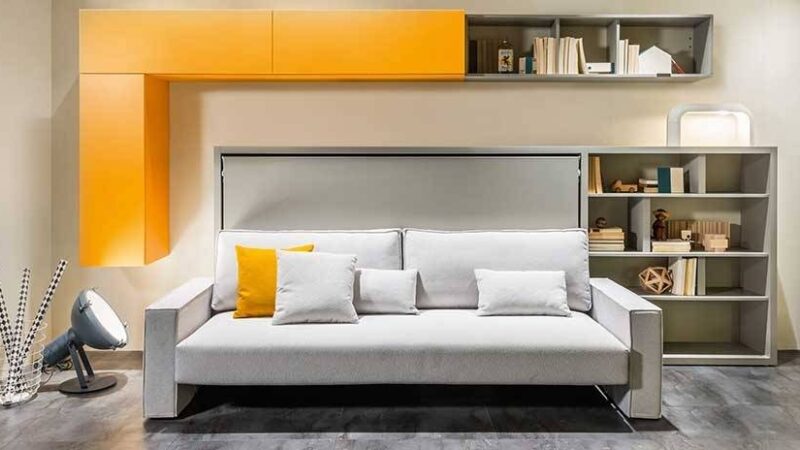 mueble con sofá cama abatible horizontal. Combinación de gris y amarillo con estantes a juego.