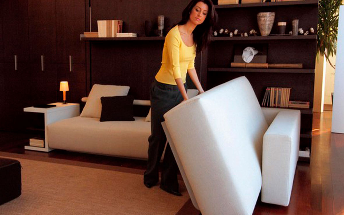 Cama abatible de matrimonio con sofá rinconero y almacenaje inferior integrado.