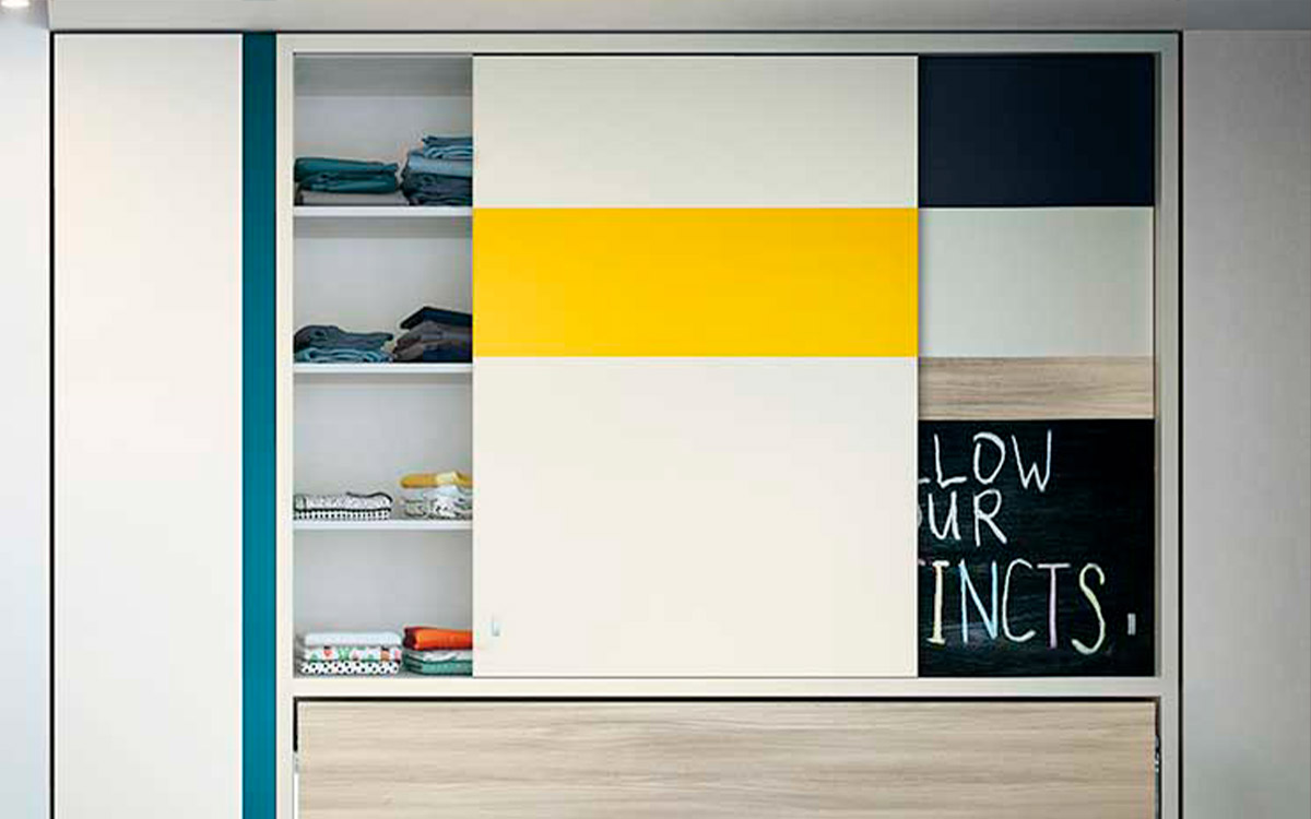 Cama individual abatible con armario superior de puertas correderas y estantes integrados.