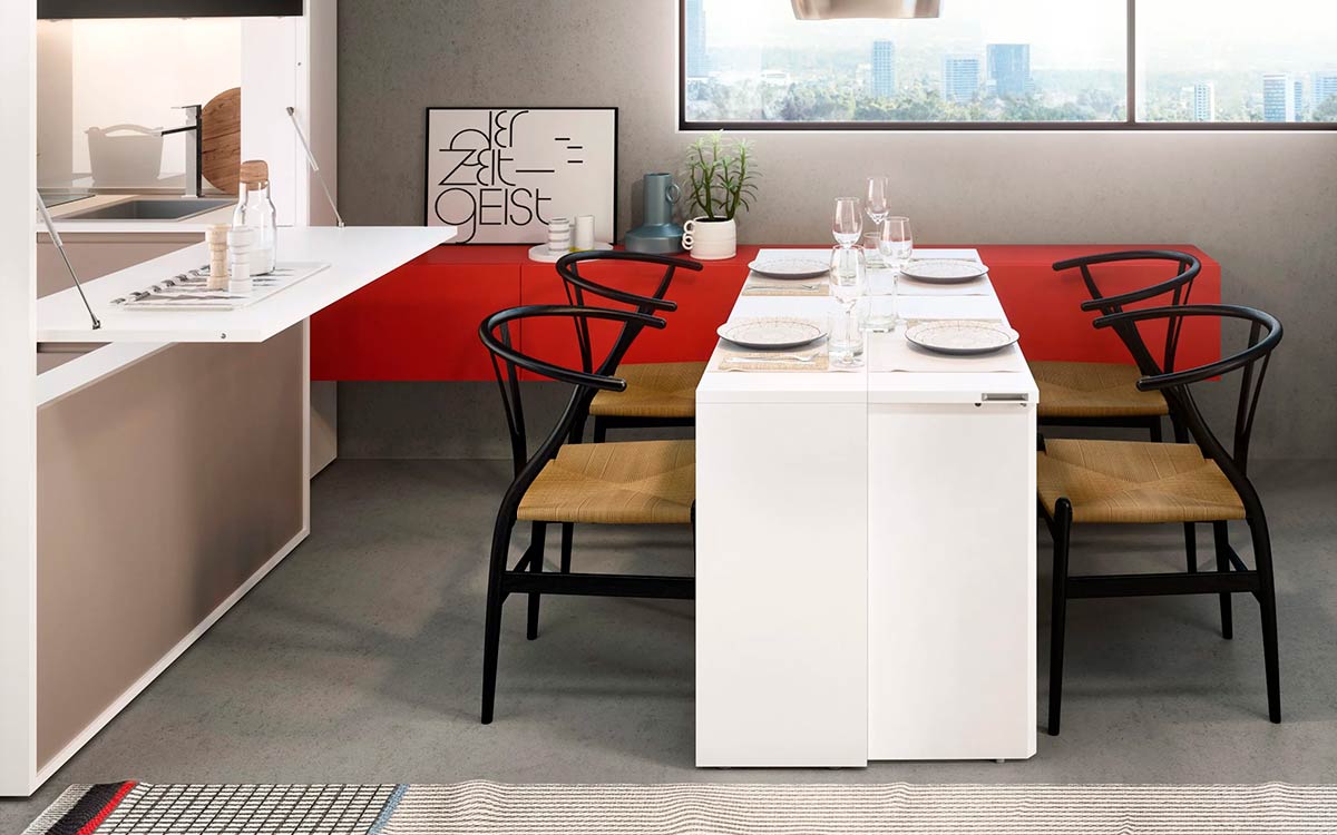 Módulo de cocina y comedor escamoteable con mesa y electrodomésticos integrados.