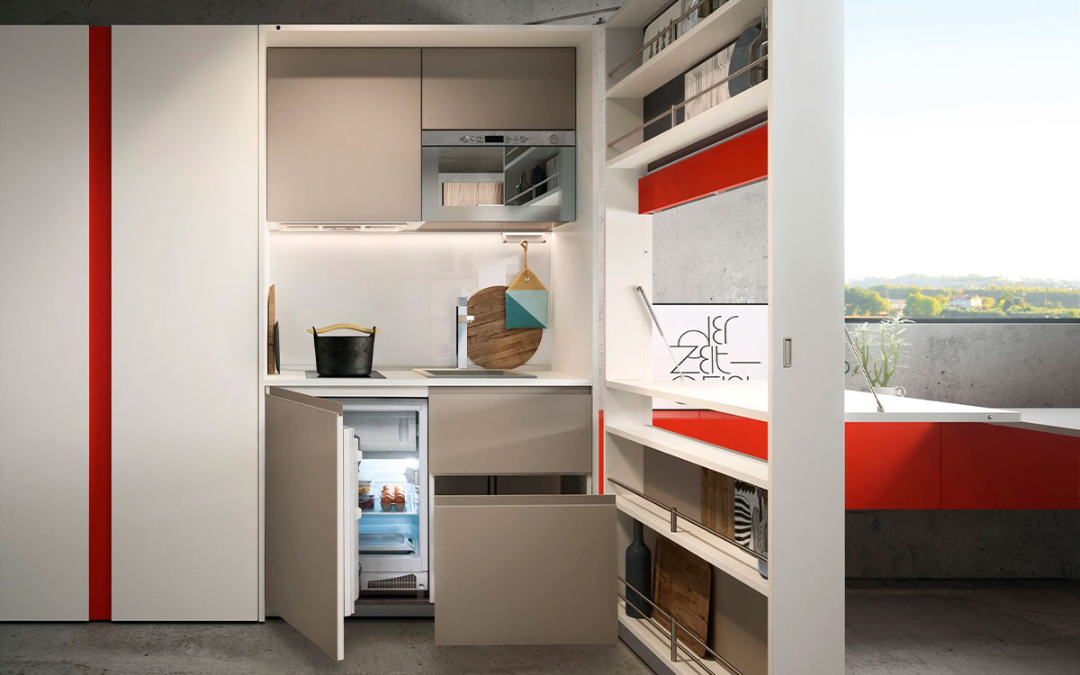 Módulo de cocina y comedor escamoteable con mesa y electrodomésticos integrados.