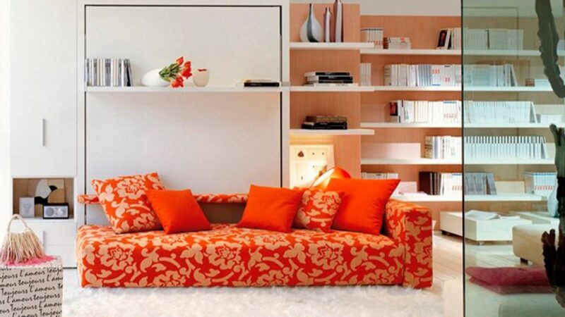 Mueble cama abatible de matrimonio con sofá diván delantero y estantería integrada.