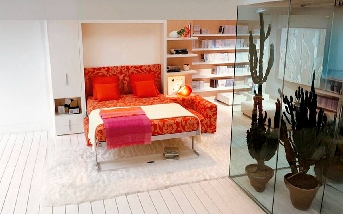 Mueble cama abatible de matrimonio con sofá diván delantero y estantería integrada.