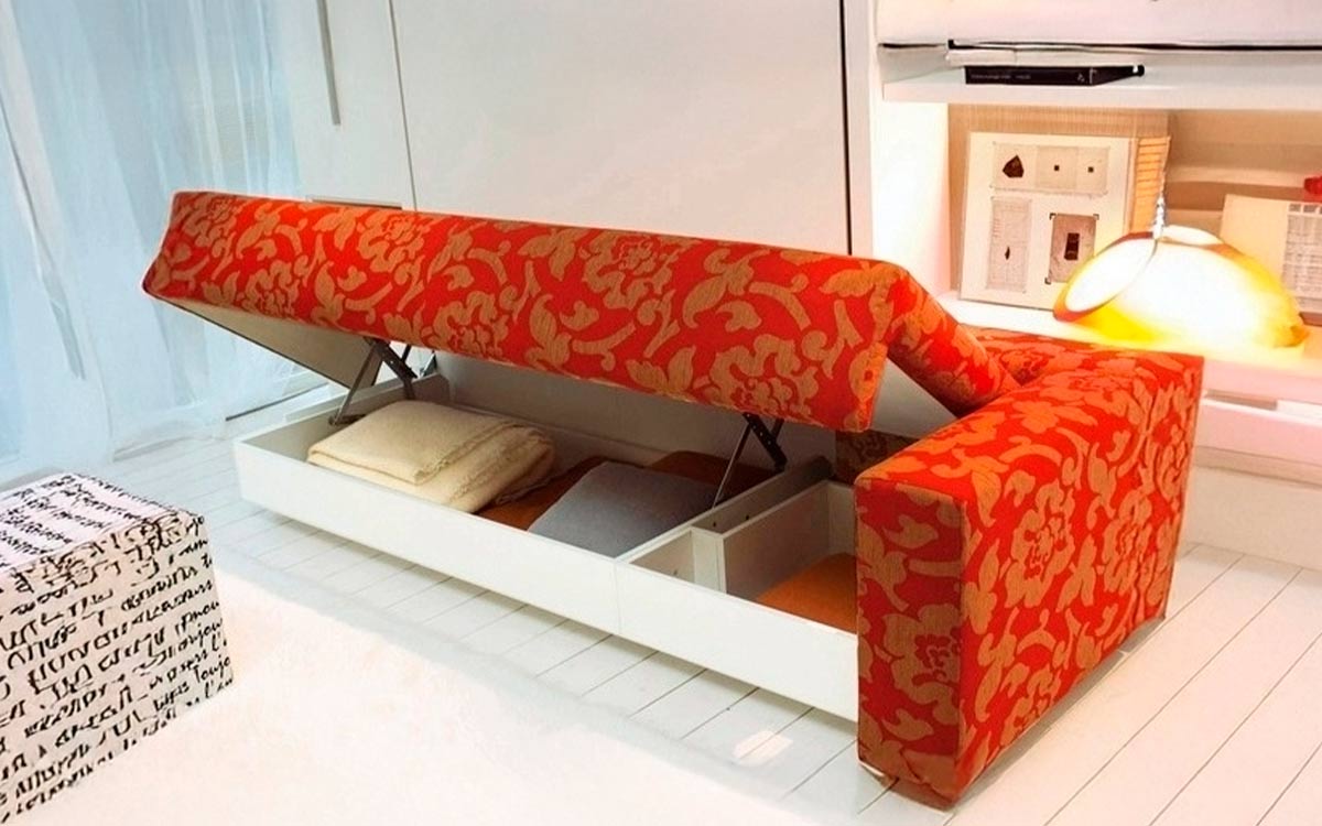 Mueble cama abatible de matrimonio con sofá diván delantero y estantería integrada.