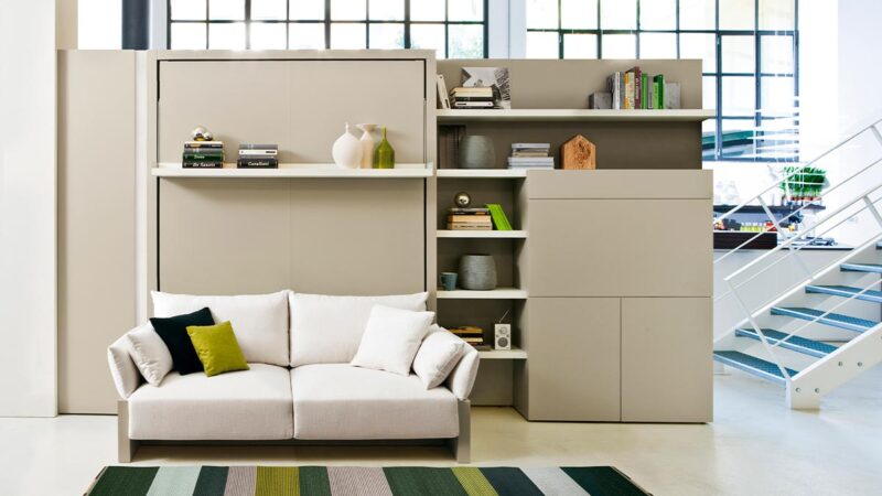 Mueble cama abatible con sofá arcón delantero y cómoda estantería integrada.