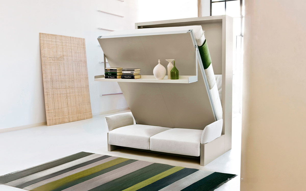 Mueble cama abatible con sofá arcón delantero y cómoda estantería integrada.