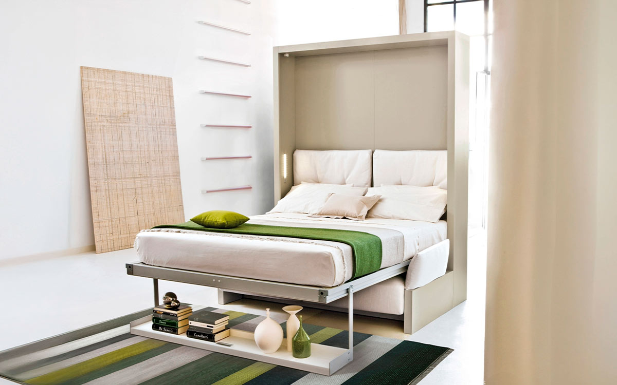 Mueble cama abatible con sofá arcón delantero y cómoda estantería integrada.